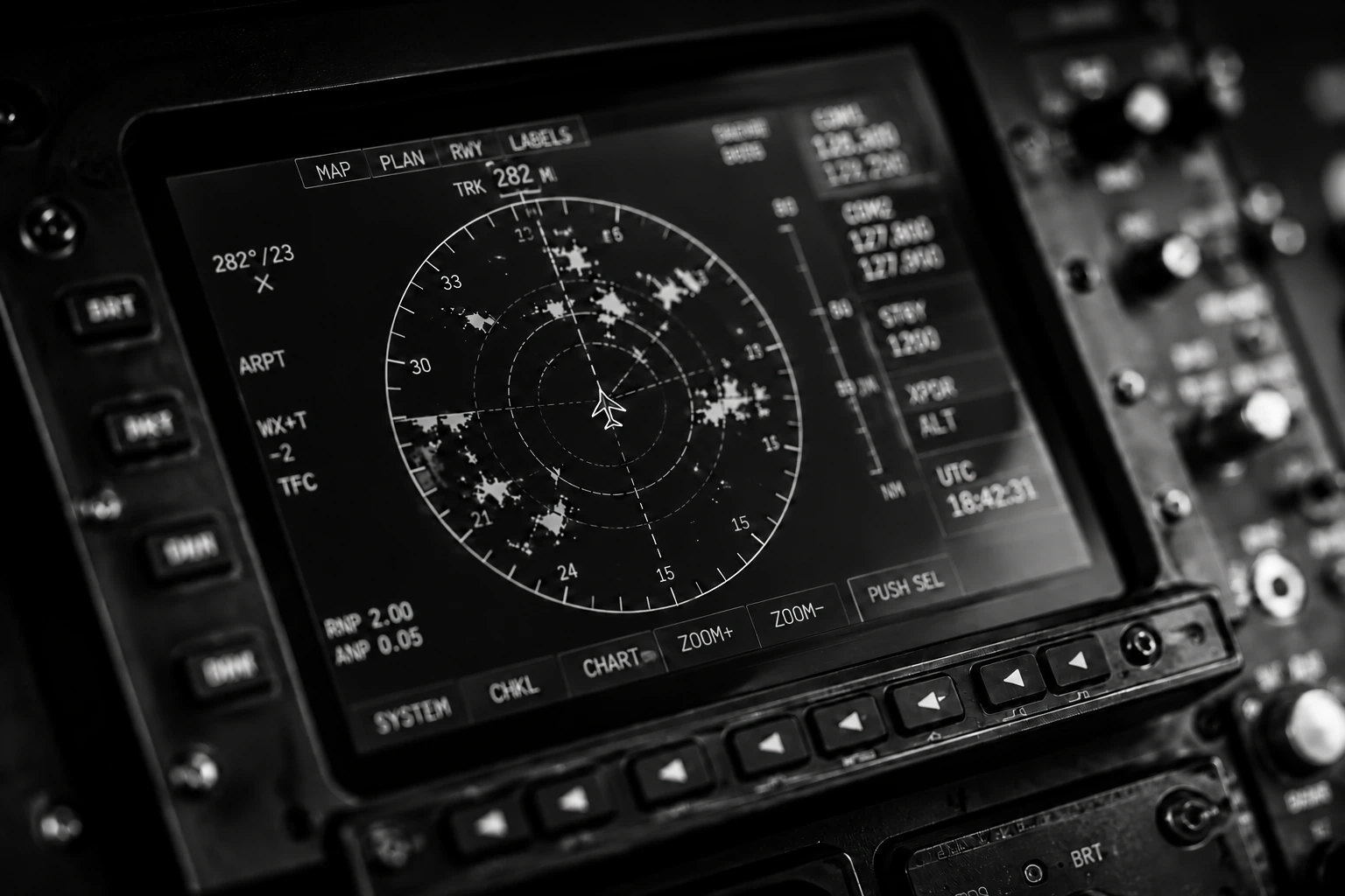 Black-and-white close-up of an avionics navigation display and cockpit controls